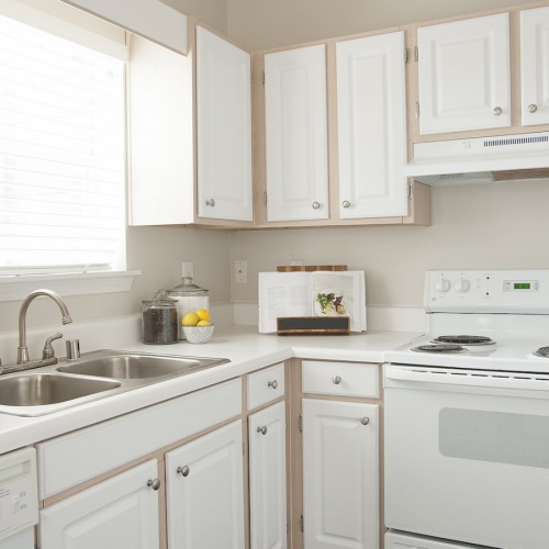 Spacious and well lit kitchen with wood floors and white appliances 